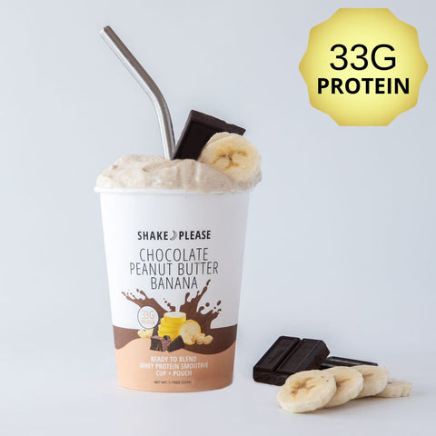 Premade chocolate peanut butter banana protein smoothie in a white cup with a brown lid labeled 33g protein, with fresh banana slices and a spoonful of peanut butter beside it.