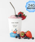 Premade vanilla berry protein smoothie in a white cup with a purple lid labeled 24g protein, surrounded by fresh strawberries and blueberries, ready to blend.